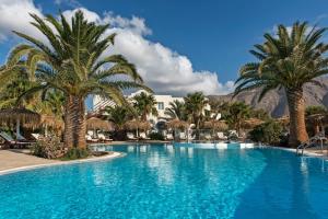 a swimming pool with palm trees and a hotel at Atlantis Beach Villa in Perivolos