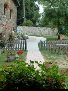 um jardim com uma parede de pedra e um caminho em Le Moulin de Drapras em Chemillé