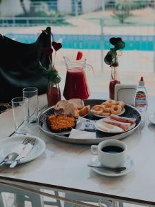 einen Tisch mit einem Teller Essen und einer Tasse Kaffee in der Unterkunft Rafa's Pousada Encantos de Minas in Três Corações