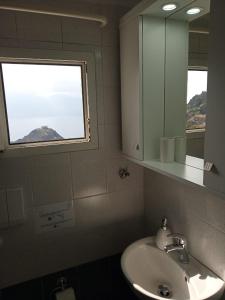 ein Bad mit einem Waschbecken, einem Spiegel und einem Fenster in der Unterkunft Studio Balkoni in Plaka Milos