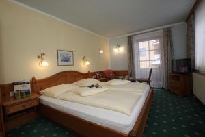 a bedroom with a large bed and a television at Hotel Sonne in Sankt Johann in Tirol