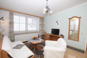 a living room with two white chairs and a table at Hotel Sonne in Sankt Johann in Tirol