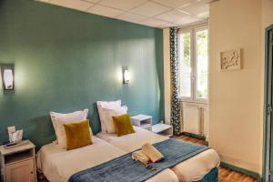 due letti in una stanza con pareti verdi di Hôtel Les Corps Saints ad Avignone