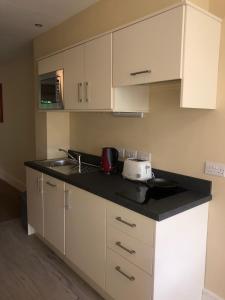 a kitchen with white cabinets and a black counter top at Castle Oaks House Hotel in Limerick