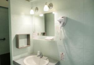 un bagno con un lavandino e un telefono a parete di Hôtel Les Corps Saints ad Avignone