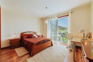 a bedroom with a bed and a desk and a window at Villa Sol in Ponta do Sol +31 photos