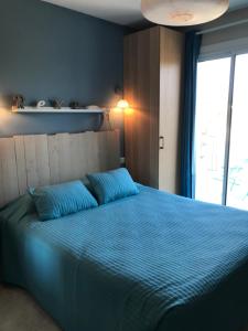 sypialnia z łóżkiem z niebieską pościelą i oknem w obiekcie Logis Hôtel Le Manoir & Lounge w Apt