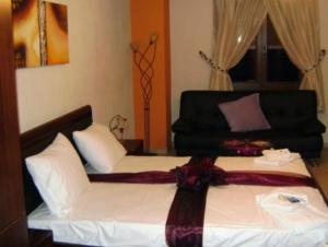 ein Schlafzimmer mit einem Bett mit weißer Bettwäsche und einem schwarzen Sofa in der Unterkunft Guesthouse To Fragma in Lithótopos