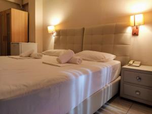 a bedroom with a large white bed with two pillows at Delfini Hotel in Piraeus