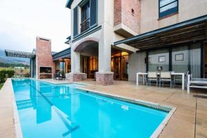 a large swimming pool in front of a house at Farm Stay Winelands in Paarl