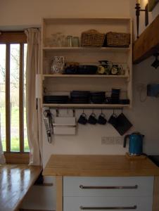 a kitchen with a counter and shelves with dishes at Manor Holding Byre in Bewdley