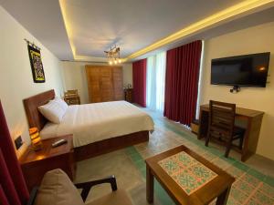 a hotel room with a bed and a tv at Pink Tulip Hoi An in Hoi An