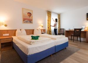 a woman standing in a hotel room with a bed at Hotel Ebnet in Mutterstadt