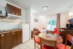 a kitchen and a living room with a table and chairs at Comfort Suites Pau Idron in Idron