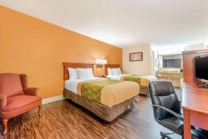 a hotel room with two beds and a chair at Econo Lodge Louisville Downtown in Louisville