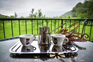 a tray with two cups and a vase on a table at Bungalovi Ključ in Ključ