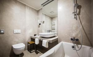 a bathroom with a sink and a tub and a toilet at Boutique & Design Hotel Navis - Small Luxury Hotels of the World in Opatija