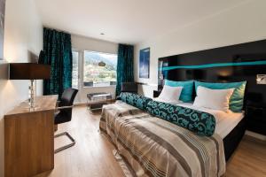 a bedroom with a bed and a desk and a window at Quality Hotel Sogndal in Sogndal