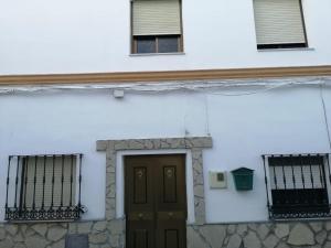 un edificio blanco con una puerta y dos ventanas en Casa Rural Guzman, en Setenil
