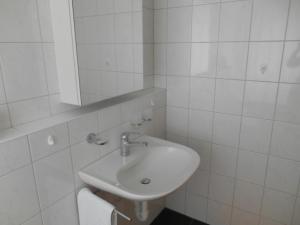 un bagno bianco con lavandino e specchio di Vazerol a Lenzerheide