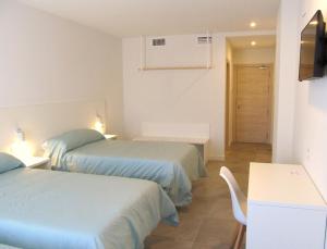 Cette chambre comprend deux lits, une table et une télévision. dans l'établissement Hotel Gran Sol De Extremadura, à Montijo