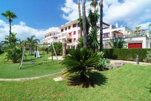 um parque infantil com um baloiço num quintal com um edifício em El Palmeral I em Denia