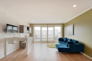 a living room with a blue couch and a table at K-Apart Hotel & Boardinghouse in Hürth