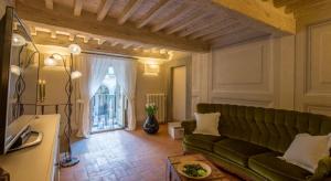 a living room with a green couch and a window at The house with steam room, jacuzzi and theater view in Cortona