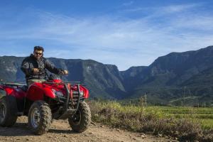 a man riding a red atv on a dirt road at Refúgio Ecológico Pedra Afiada in Praia Grande