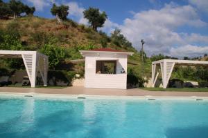 - un petit bâtiment blanc à côté d'une piscine dans l'établissement Agriturismo Vulcano, à Crosia