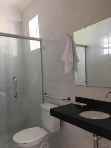 a bathroom with a toilet and a sink and a mirror at Recanto do Teimoso suites in Ubatuba