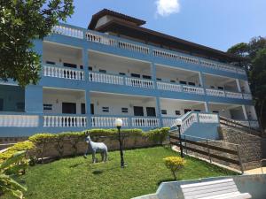 
a white horse standing in front of a white house at Recanto do Teimoso in Ubatuba
