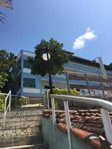 a building with a tree in front of a building at Recanto do Teimoso suites in Ubatuba