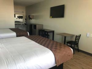 ein Hotelzimmer mit 2 Betten, einem Tisch und einem TV in der Unterkunft Mariner Inn in Galveston