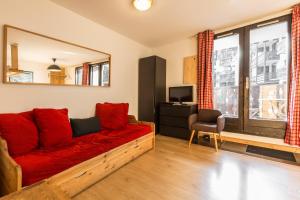een woonkamer met een rode bank en een televisie bij Apartment Marcel in Chamonix-Mont-Blanc