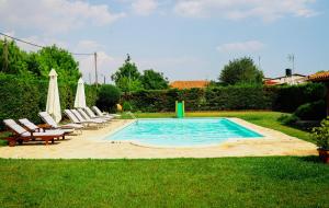 a swimming pool with chairs and umbrellas in a yard at Renaissance Holidays Villa in Nea Kallikrateia