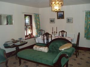 a living room with a green chair and a table at Barn-Gill House in Thirlmere