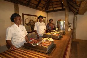 tres chefs parados frente a un buffet de comida en Tembe Elephant Park Lodge, en Sihangwane