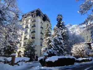 a building with snow covered trees in front of it at Résidence Majestic in Chamonix