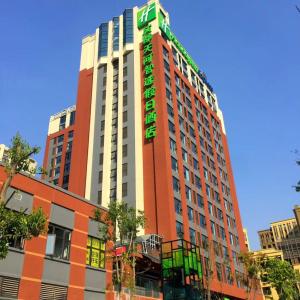 Holiday Inn Express Chengdu Tianhe, an IHG Hotel في Pi: مبنى طويل عليه علامة خضراء