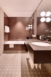 a bathroom with a sink, mirror, and bathtub at Hotel Walhalla in St. Gallen