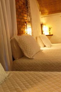 a bedroom with two beds and a brick wall at Pousada La Villa Caraiva in Caraíva