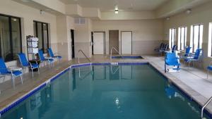 a swimming pool with blue chairs in a building at Holiday Inn Express & Suites Deming Mimbres Valley, an IHG Hotel in Deming