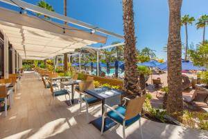 ein Restaurant mit Tischen und Stühlen und der Strand in der Unterkunft Corallium Beach by Lopesan Hotels - Adults Only in San Agustín