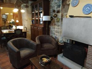 a living room with two chairs and a fireplace at Apartahotel Montecaoru in Arenas de Cabrales