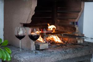 two glasses of wine sitting next to a fire at Hauzify I Villa Parc in Hospitalet de l'Infant