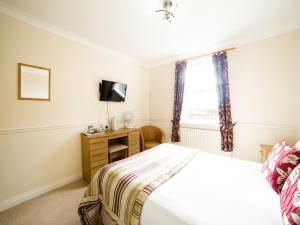 Schlafzimmer mit einem Bett, einem TV und einem Fenster in der Unterkunft OYO White Horse Lodge Hotel, East Thirsk in Thirsk