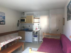 eine kleine Küche mit einem lila Sofa in einem Zimmer in der Unterkunft Boost Your Immo Les 2 Alpes Andromede 165 in Vénosc