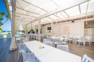 a restaurant with white tables and white chairs at Babai Village Resort in Tertenìa
