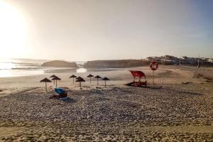 a beach with several umbrellas on the sand at Ocean Pearl Baleal in Ferrel